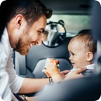 Father buckles his baby into a child car seat.